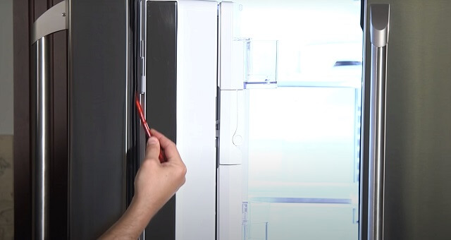 мастер с помощью клея пропитывает место крепления будущей манжеты дверцы холодильника